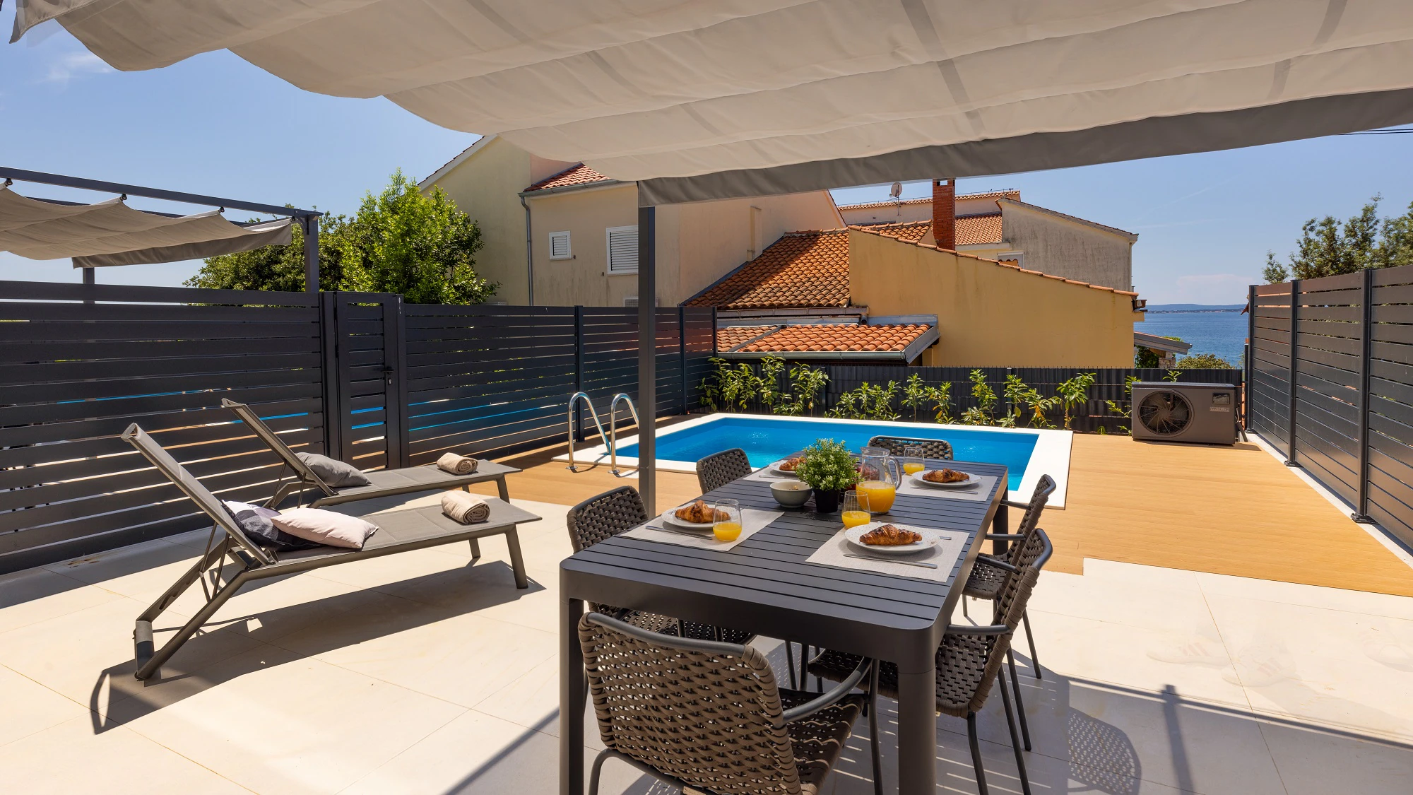 Pool terrace with dining and sun loungers at Three-Bedroom Apartment with Private Pool Near the Sea