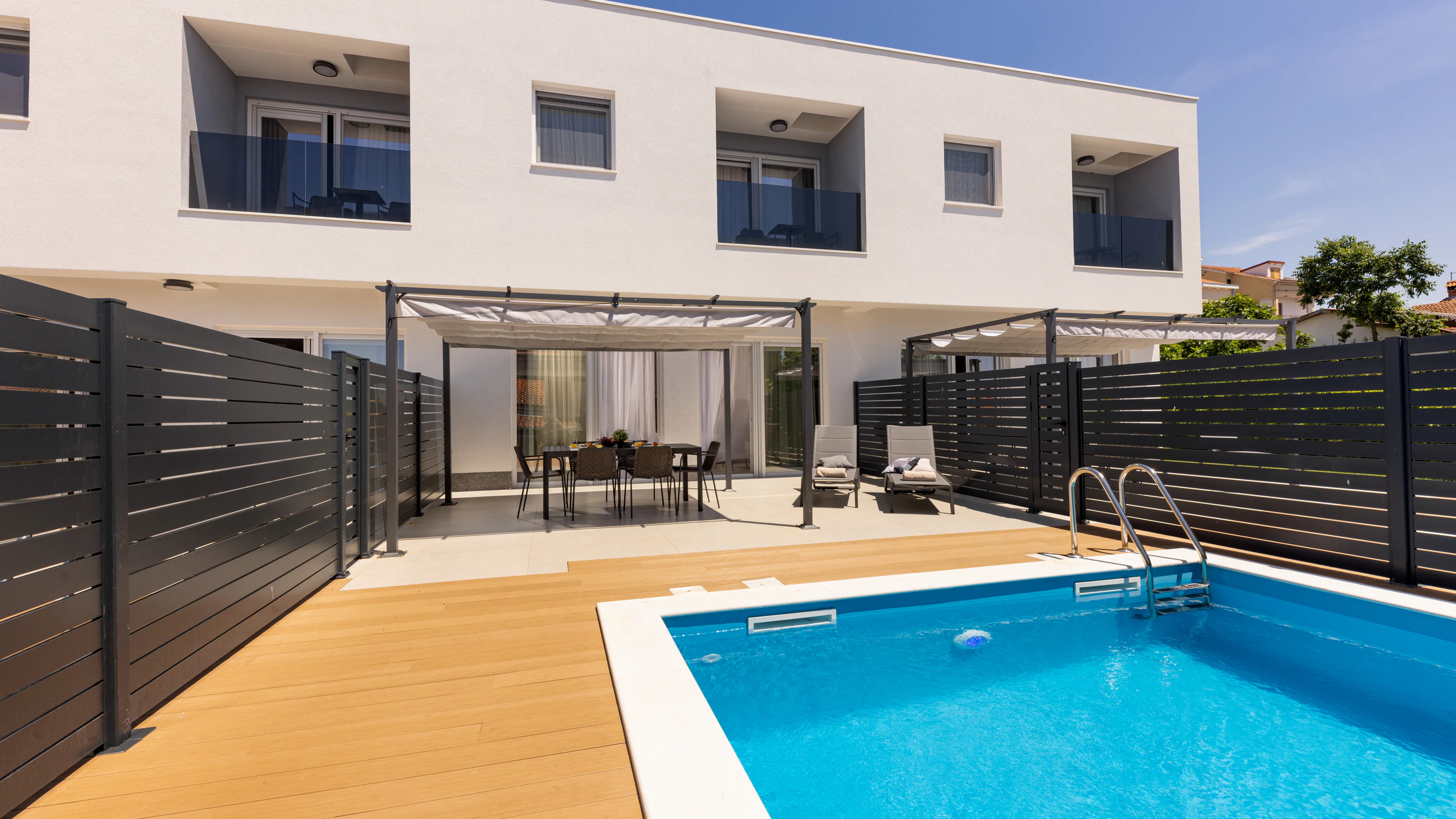 Pool terrace with dining and sun loungers at Three-Bedroom Apartment with Private Pool Near the Sea